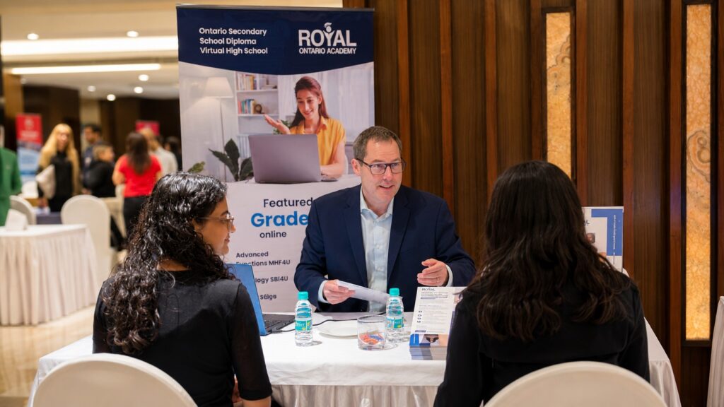 Director of New Students at Royal Ontario Academy speaking with prospective students at a stufy fair.